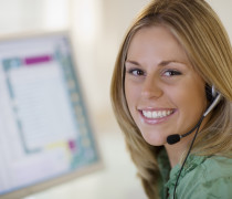 Smiling woman with headset and computer monitor