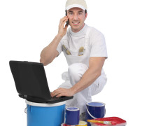 Decorator with laptop and tins of paint