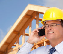 Contractor in Hardhat at Construction Site Talks on His Cell Phone.