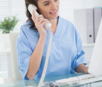Smiling doctor phoning and using computer in medical office