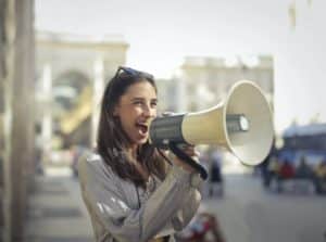 Businesswomen using a megaphone to magnify her voice - human answering service